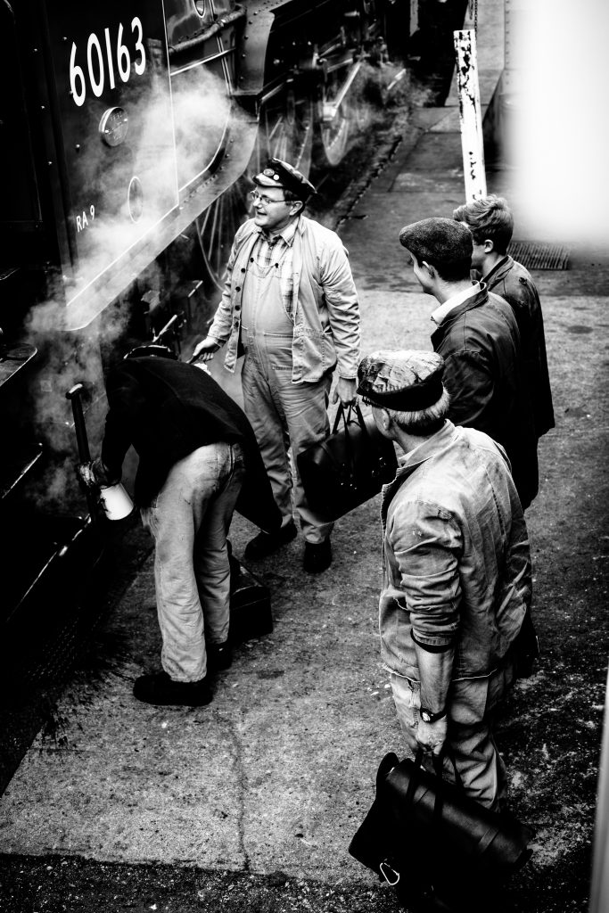 5 men next to steam train